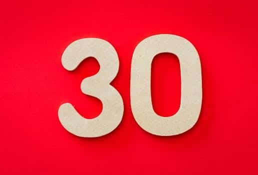 Close-up of cardboard number 30 on a bright red background, ideal for birthday or anniversary themes.