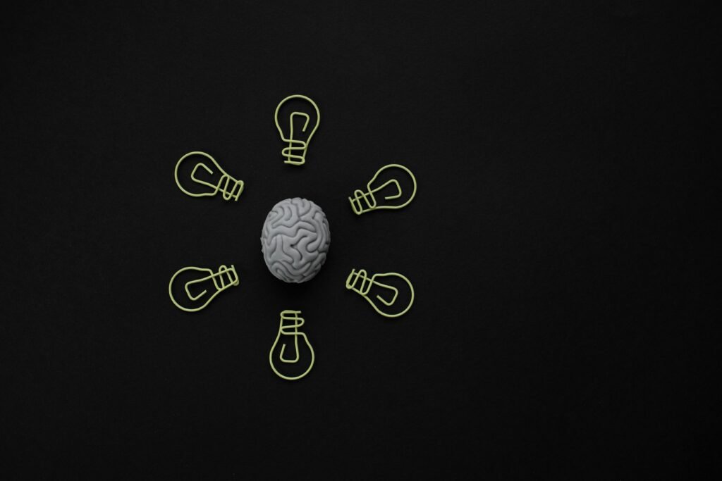 Conceptual photo of a brain surrounded by light bulb clips on black background.